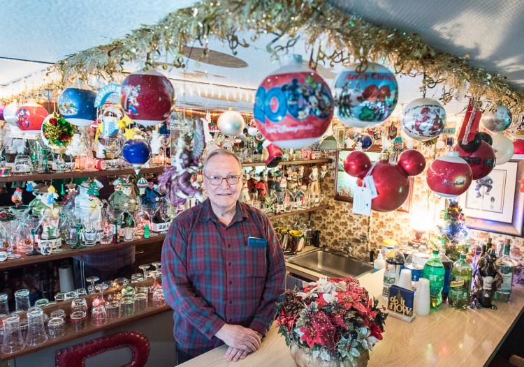 Standing behind a bar ready for a party, Roland Bergeron of Auburn has decorated the inside of his historic family homestead with thousands of Christmas decorations every year since he was a boy.