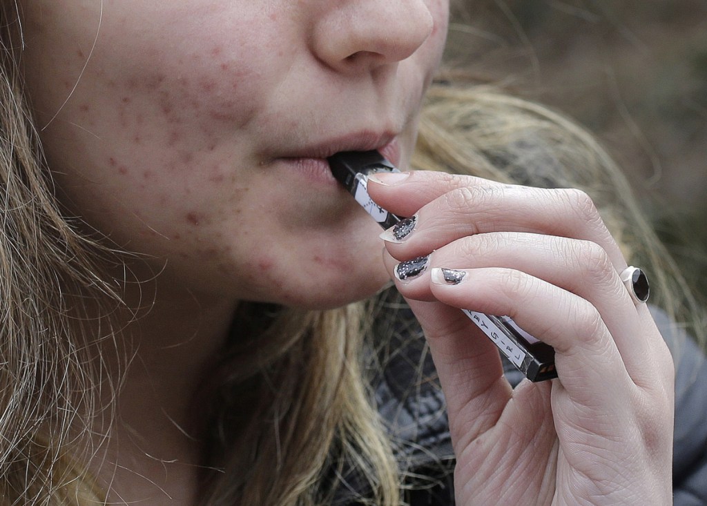 A high school student uses a vaping device near a school campus in Massachusetts. The rise of vaping has reversed recent progress in turning kids away from nicotine, researchers say.