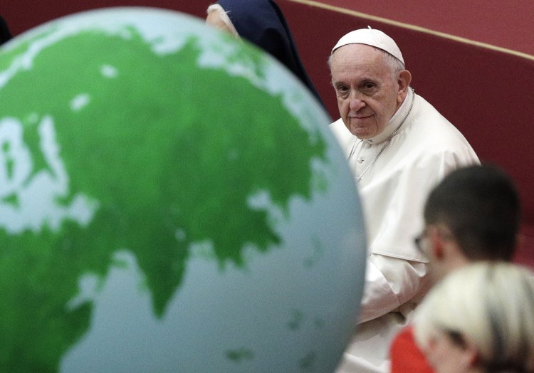 Pope Francis holds an audience with families from a Vatican charity that helps mothers and children in need, at the Vatican on Sunday, the eve of his 82nd birthday. The globe adorned his cake.