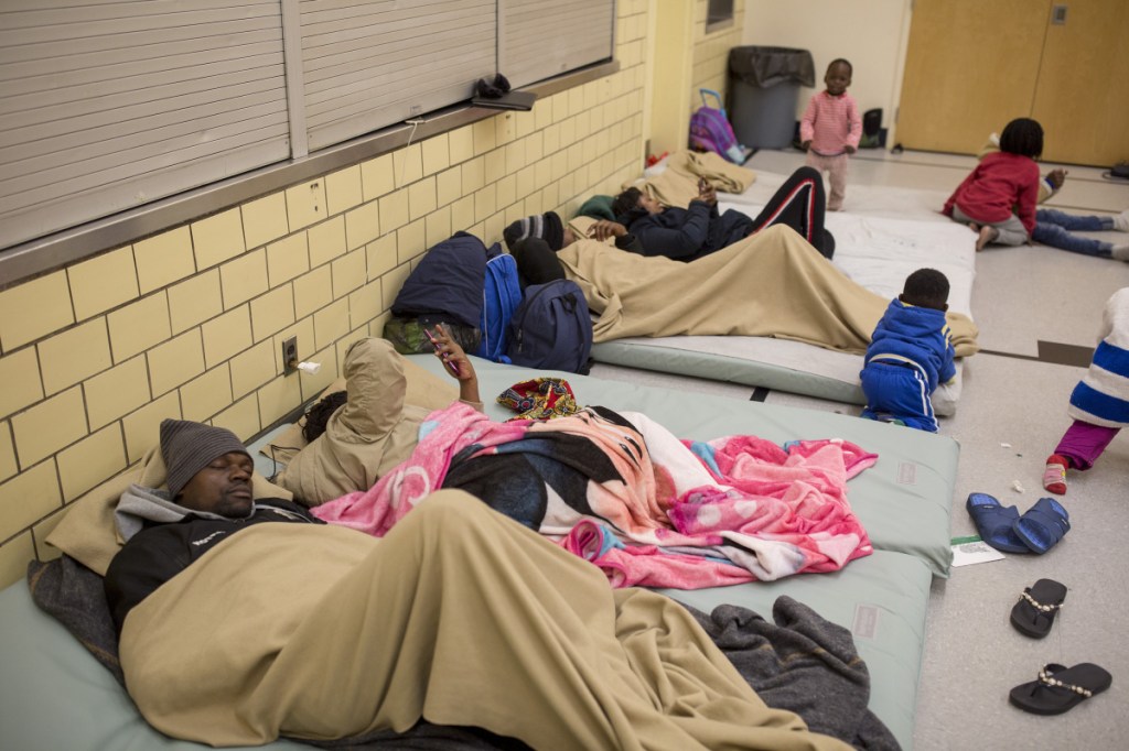 Earlier this month, 199 noncitizens sought space at Portland's Family Shelter, compared with 61 five years ago. The surge of asylum seekers means many must sleep in overflow spaces, and scarce affordable housing is keeping them in shelters for longer periods. Above, migrants prepare for bed at the Salvation Army gymnasium. 