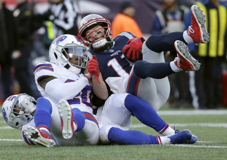 New England Patriots wide receiver Julian Edelman, right, rolls over Buffalo Bills defenders including Rafael Bush on the way to a touchdown after catching a pass during the second half of the Patriots' 24-12 win on Sunday in in Foxborough, Mass.