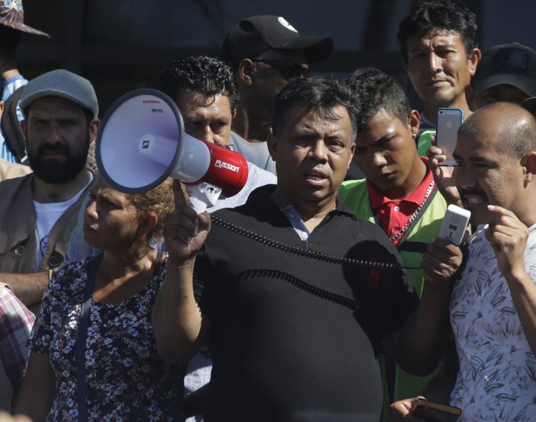 Migrant activist Irineo Mujica, center, of the group Pueblo Sin Fronteras holds a megaphone as a Central American migrant speaks to reporters during a news conference in Tapachula, Mexico, in October.