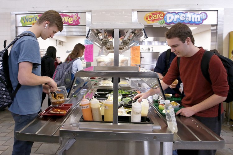 Sophomores Morrison Doucette, left, and Ethan Russell load up at the salad bar at Bonny Eagle High School. The Trump administration may have rescinded nutrition requirements, but some districts are keeping it old school.