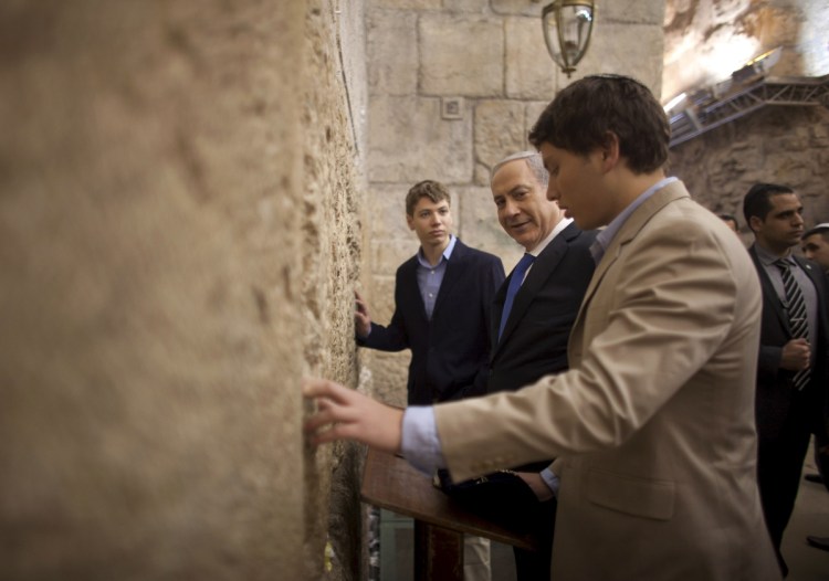 Israeli Prime Minister Benjamin Netanyahu, center, prays with his sons Yair Netanyahu, left, and Avner Netanyahu at the Western Wall in Jerusalem's old city.  Netanyahu's ruling coalition has disbanded and called an election for April 9.