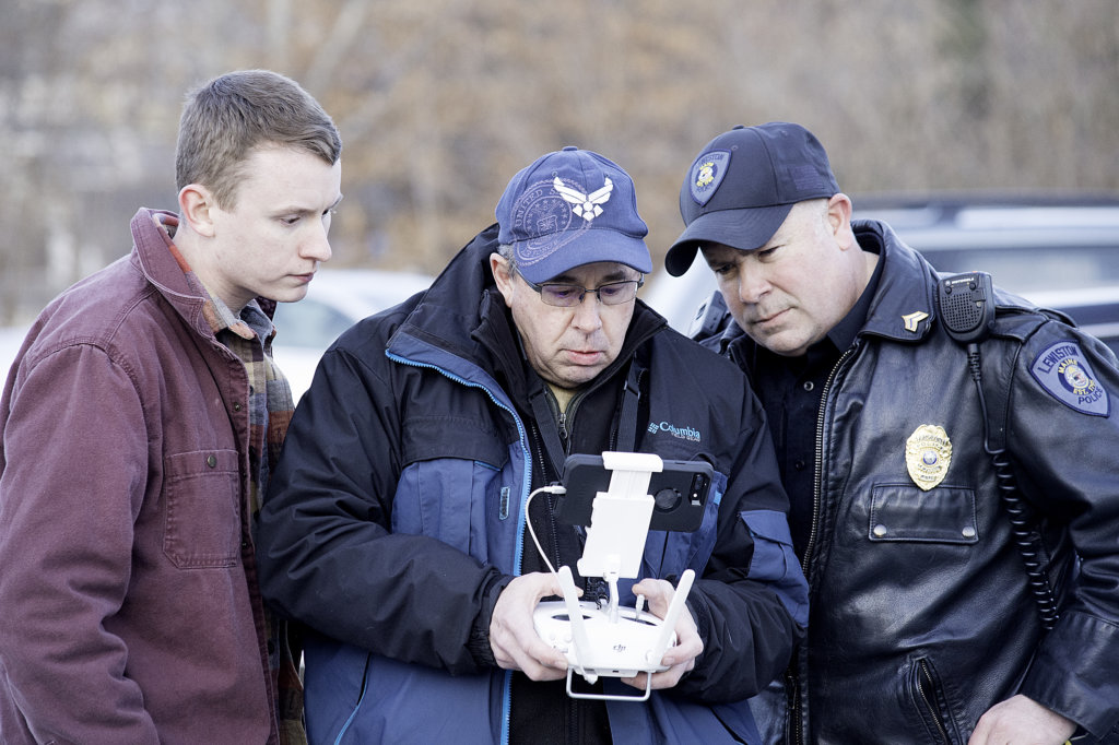 Robert Ullrich, right, of the Lewiston Police Department looks over the shoulder of Sun Journal photographer Russ Dillingham as Dillingham uses his drone to help search the woods for a 59-year-old man who was found dead from a self-inflicted gunshot. Dillingham's son, Ryan, is at left. 