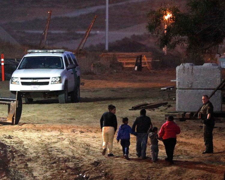 Migrants traveling with children walk up a hill to a waiting U.S. border patrol guard just inside San Ysidro, California, after climbing over the border wall from Playas de Tijuana, Mexico on Monday.