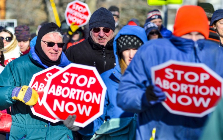 Anti-abortion rally participants walk from the St. Michael School gymnasium toward the Maine State House on Saturday in Augusta.