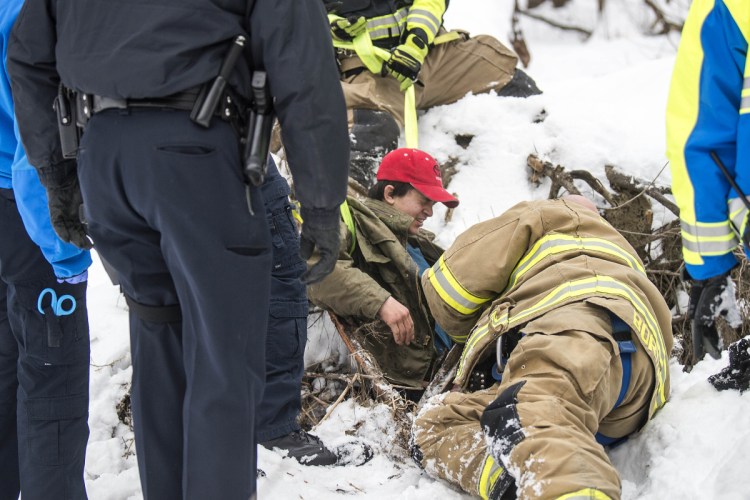 Waterville fire-rescue technician Glen Bordas lies on the ground as he and other rescue workers from Delta Ambulance and the Waterville police and fire departments pull Dias Greene, 15, to safety Jan. 5 after he fell into a hole in the woods south of the Hathaway Creative Center in Waterville.