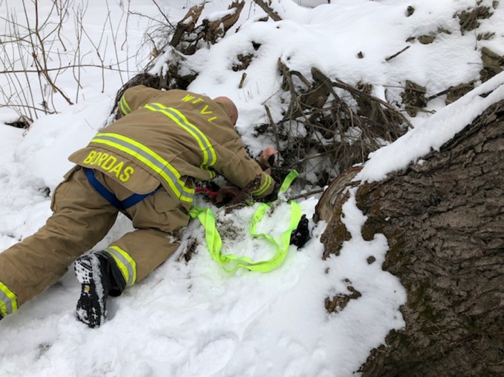 Waterville fire-rescue technician Glen Bordas lies on the ground Jan. 5 as he talks calmly to the boy, who slipped into a hole, and explains to him how they plan to get him out by strapping webbing around his body and pulling him slowly upward.