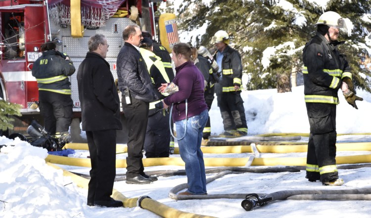Homeowner Tracy Moody speaks with friend Larry Jones, left, and Skowhegan Fire Chief Shawn Howard as firefighters extinguish the fire that destroyed her mobile home in Norridgewock on Wednesday.