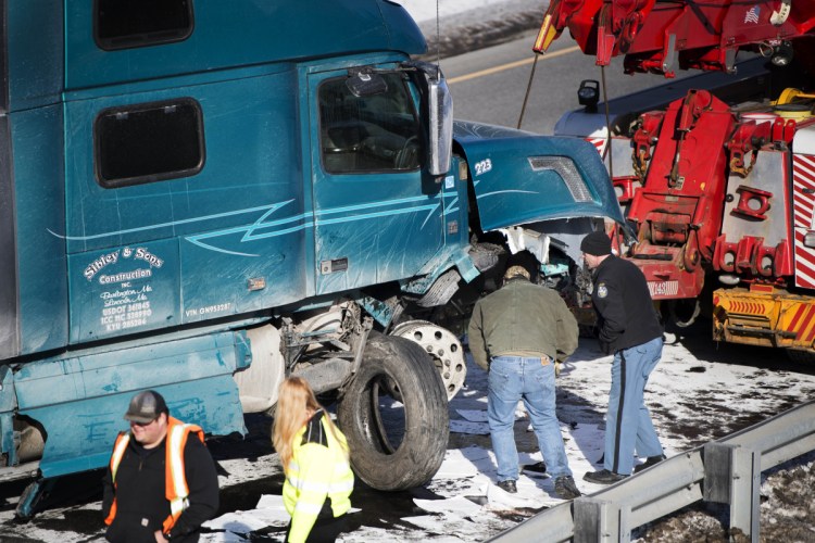 A Maine State Police trooper inspects the damage to a tractor-trailer that struck an Interstate 95 guardrail Saturday on the northbound side of exit 120 in Sidney.