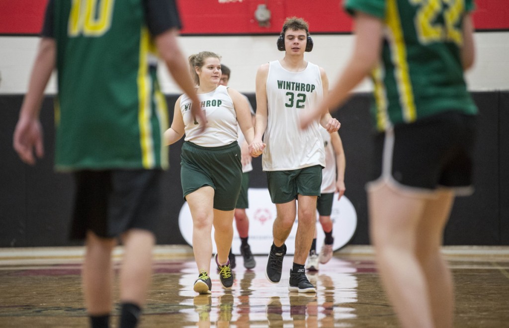 Winthrop High School's Samantha Neumann (11) holds hands with teammate Lukas Thompson (32) as they run back on defense against Massabesic at the Unified basketball tournament Saturday at Thomas College in Waterville.