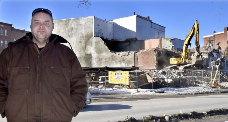 Tom Greenwood stands off Front Street in Waterville as a demolition crew tears down the former Camden National Bank on Thursday.