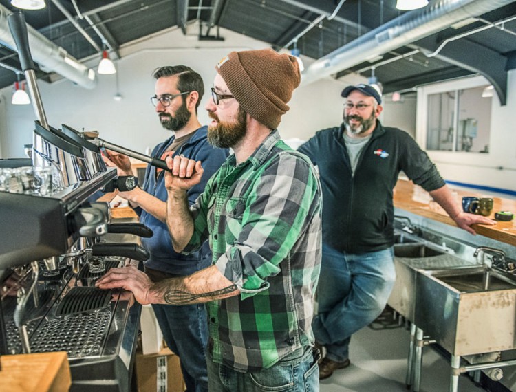 Nathan Hahn of Coffee by Design, left, walks Willis Croninger through the process of pulling the first press of espresso at Side by Each Brewing Co. in Auburn. Owner Ben Low looks on, right.