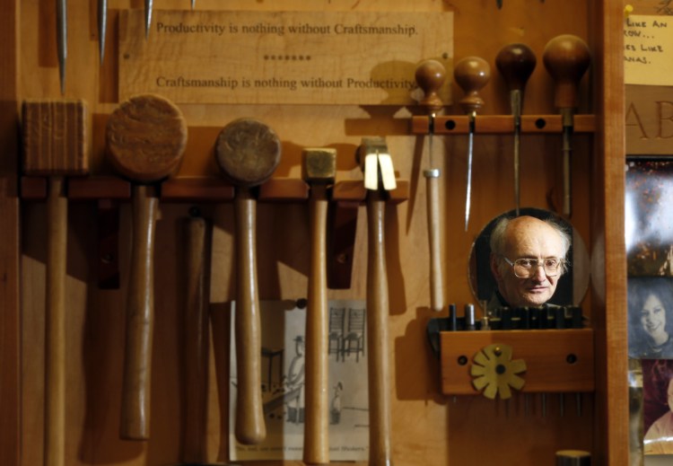 Master woodworker Christian Becksvoort is reflected in a mirror on the tool chest in his New Gloucester shop, where a sign reads "Productivity is nothing without Craftsmanship ... Craftsmanship is nothing without Productivity."