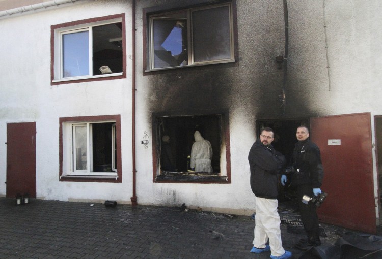 Forensic and other police experts examine the site of a fire adjacent to an escape room in Koszalin, Poland, on Saturday.The fire killed five teenage girls locked inside the escape room and injured a man.