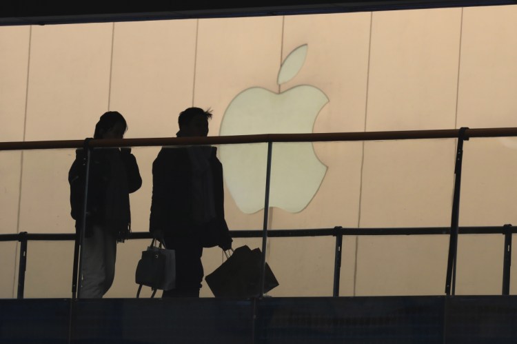 Shoppers pass by the Apple store logo Thursday at a mall in Beijing. A U.S. delegation led by a deputy U.S. trade representative, Jeffrey D. Gerrish, arrived in the Chinese capital ahead of trade talks this week.