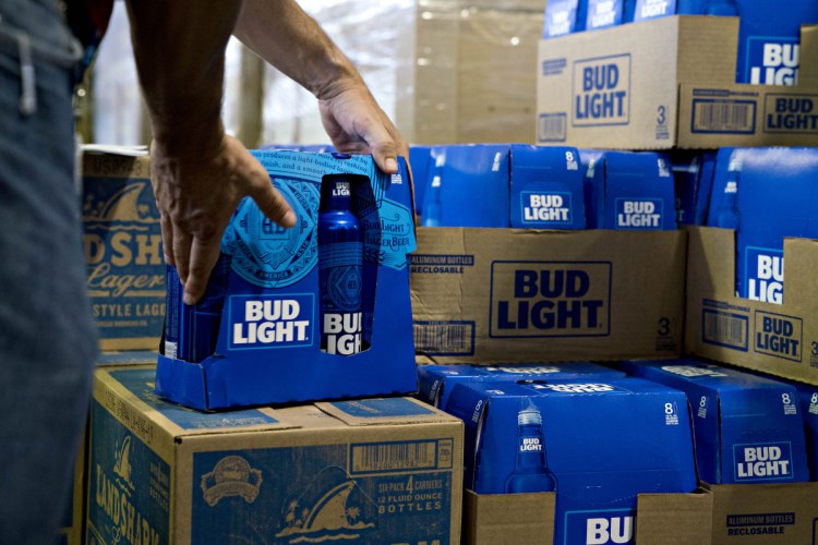 An employee adjusts bottles of Bud Light brand beer at an Anheuser-Busch InBev NV facility in Williamsburg, Va. Bud Light will begin including standard white nutrition labels on case boxes and six-packs next month.