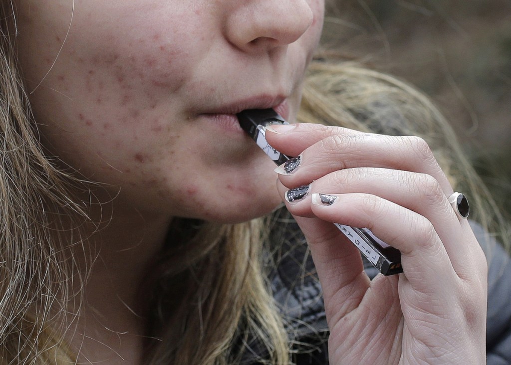 A student uses a vaping device near a school in Cambridge, Mass. Health officials are scrambling to deal with an epidemic of underage use.