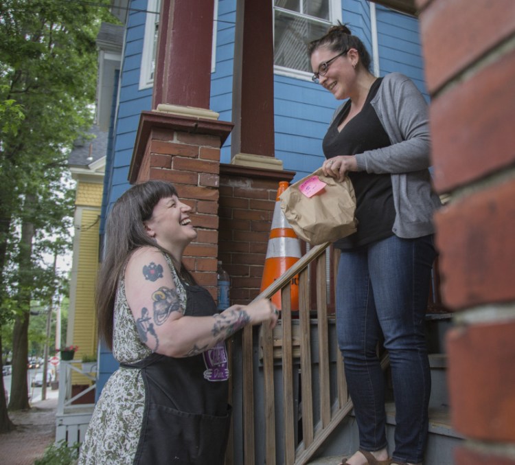 Salli Wason, left, owner of Rosanna's Ice Cream, delivers ice cream to Ann-Marie Keene in Portland in 2017. Rosanna's is closing. Wason says the business has taken a toll on her, and she's returning to school.