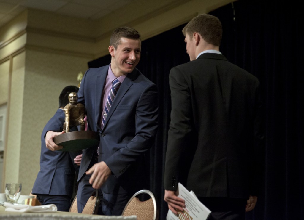 Tyler Bridge, left, of Wells is congratulated by Zack Elowitch of Portland after receiving the Fitzpatrick Trophy at the Holiday Inn by the Bay in Portland on Sunday. Elowitch and Anthony Bracamonte of Thornton Academy were the other finalists.