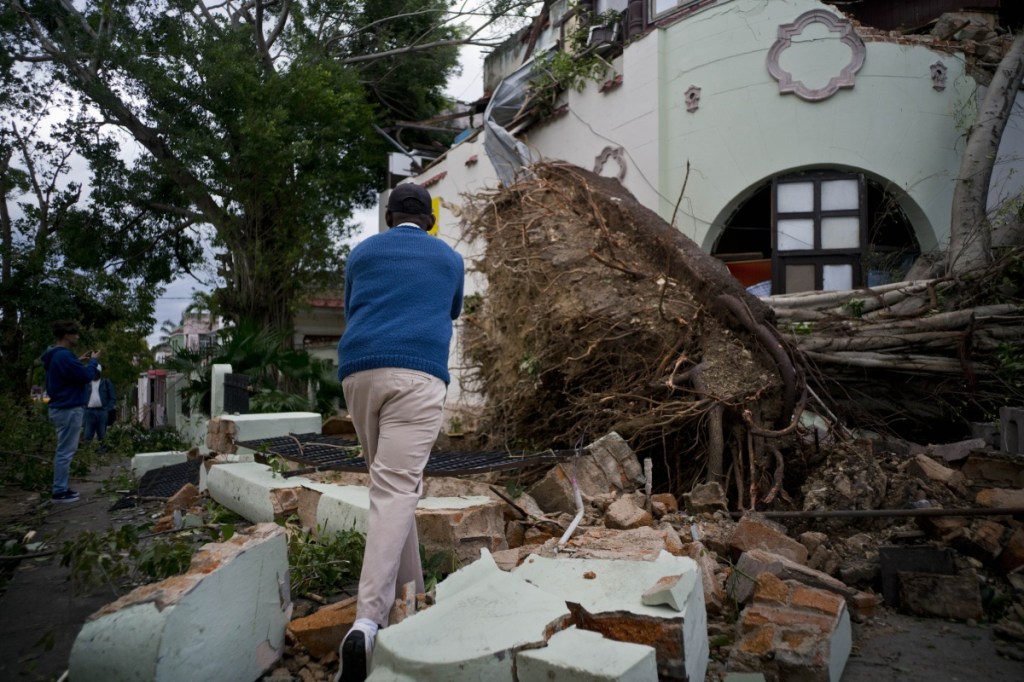 A man takes pictures of the disaster left behind by a tornado in Havana, Cuba, Monday, Jan. 28, 2019. A tornado and pounding rains smashed into the eastern part of Cuba's capital overnight, toppling trees, bending power poles and flinging shards of metal roofing through the air as the storm cut a path of destruction across eastern Havana. (AP Photo/Ramon Espinosa)