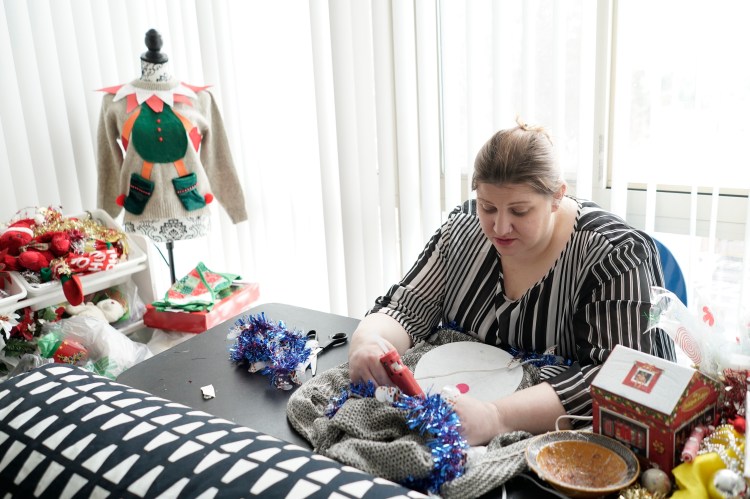 Doris Cochran works on "an ugly sweater," which she is planning to sell, Friday, Jan. 18, 2019 in her apartment in Arlington, Va., Cochran is a disabled mother of two young boys living in subsidized housing in Arlington, Virginia. She’s stockpiling canned foods to try to make sure her family won’t go hungry if her food stamps run out. She says she just doesn’t know “what’s going to happen” and that’s what scares her the most. 
