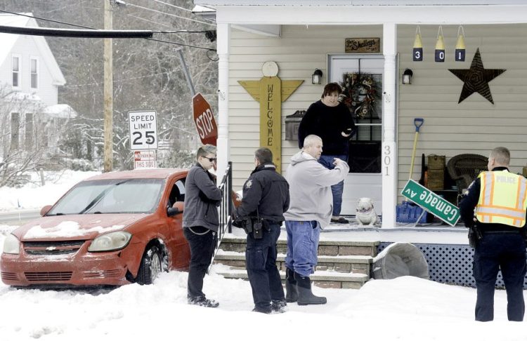 The homeowners talk with Auburn Police Sgt. Chad Syphers, right, after a car slid into the side of the house at 301 Gamage Ave. in Auburn on Tuesday. Minimal damage was done to the front porch, according to Auburn firefighters on scene. 