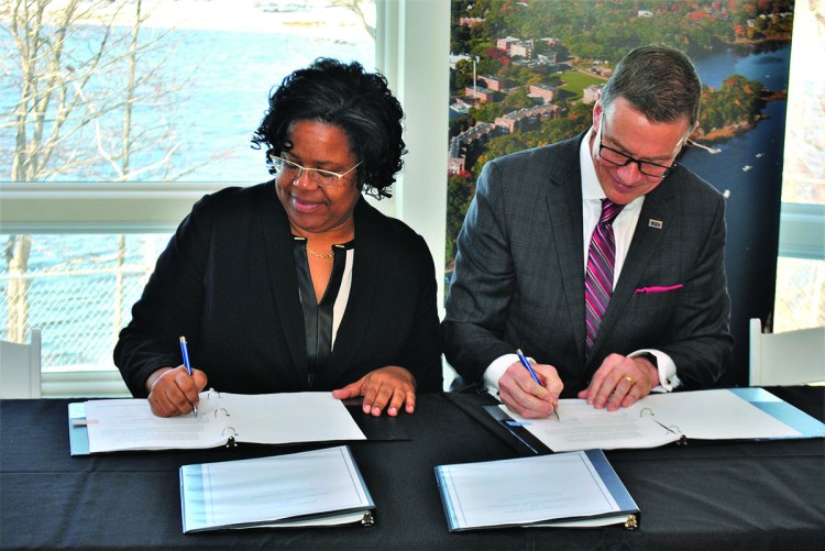 Danielle Conway, dean of the University of Maine School of Law, and University of New England President James Herbert sign an agreement between the two colleges Wednesday at the UNE campus in Biddeford.
