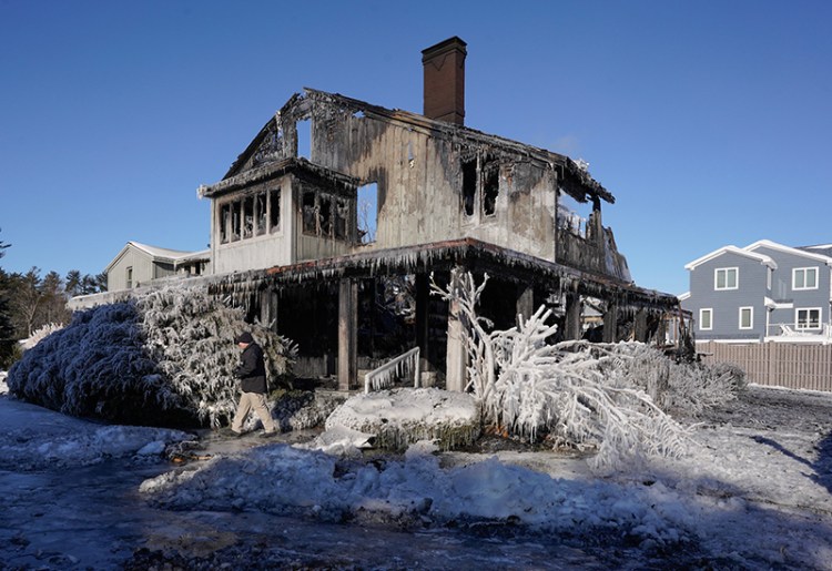 Walking past a burned house covered in ice, Chris Stanford, a senior Investigator with the State Fire Marshall’s office, examines the scene of a fire at 311 Seaside Avenue in Saco on Thursday. Frigid temperatures made fighting the structure fire difficult for firefighters. 