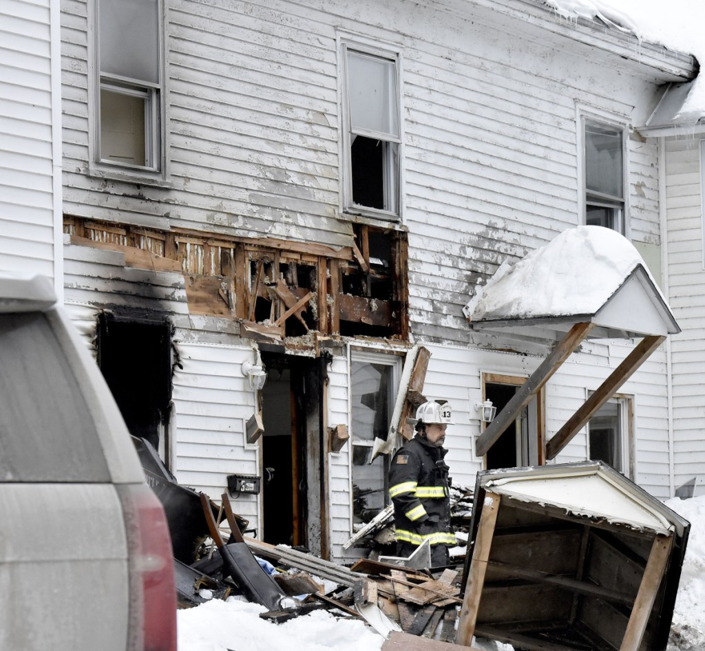 Skowhegan Fire Chief Shawn Howard exits through a fire-damaged entryway Sunday at an apartment house at 386 Water St. in Skowhegan after fire broke out there that morning.