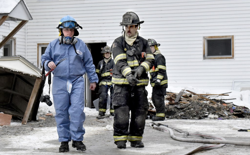 Jeremy Damren, left, of the Office of State Fire Marshal, confers with a Skowhegan firefighter Sunday while investigating the cause of a fire at 386 Water St. in Skowhegan after fire broke out there that morning.