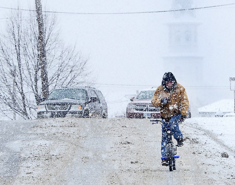 A cyclist rides through snow on U.S. 40 during a winter storm Friday in Hagerstown, Md. 