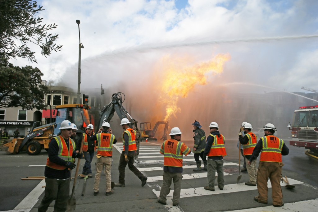 PG&E officials stand by as firefighters battle a fire following a gas explosion Wednesday in San Francisco, Calif. Utility crews scrambled to shut off the flow of gas more than two hours after the blaze began. Private construction workers cut a natural gas line, San Francisco Fire Chief Joanne Hayes-White said.