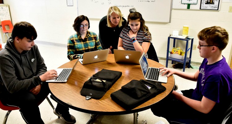 Kim Quinn Hutchinson, executive director of a computer science pilot program funded by an $881,000 grant from the Harold Alfond Foundation and to begin in August, assists Waterville Junior High School students on Thursday. From left are Dylan Mitchell, Alexa DeWitt, Leilani Gomez and Zachary London. 