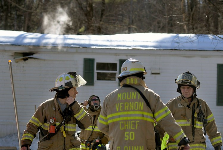 Firefighters emerge from a residence that burned Monday in Mt. Vernon. 