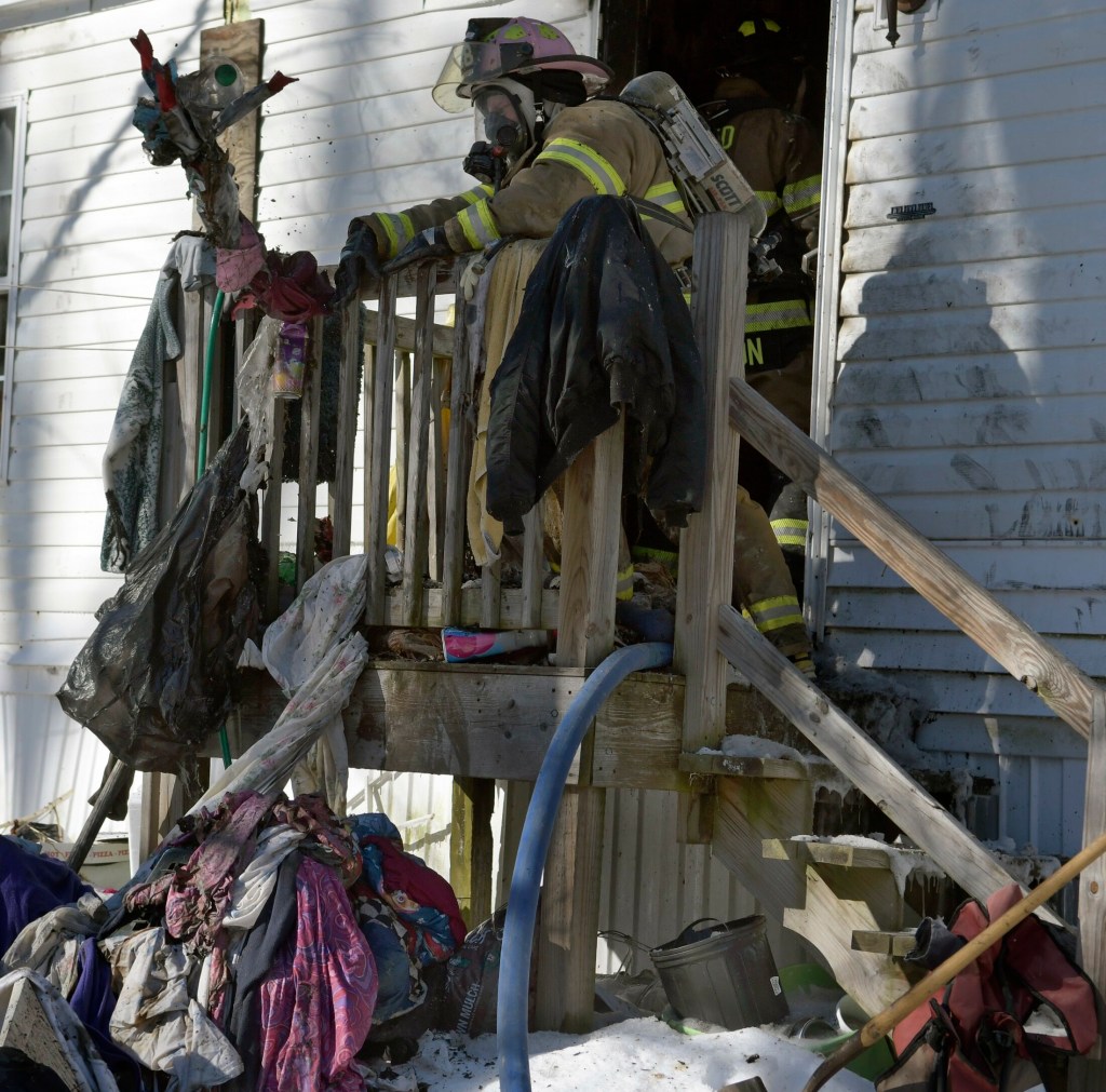 A firefighter tosses items that burned Monday during a fire at a residence in Mt. Vernon.