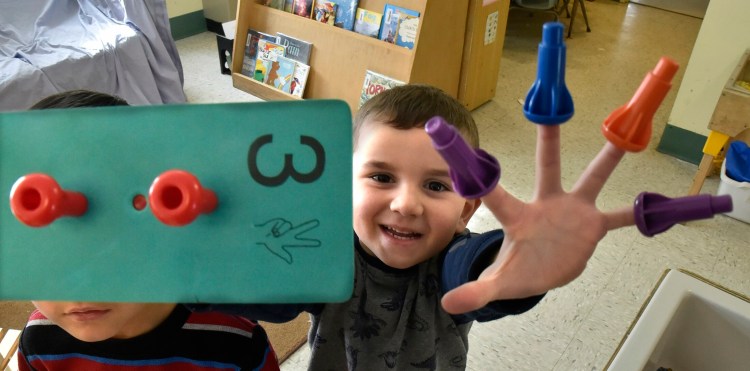 A boy shows off his fingers while playing with a puzzle at the Sweatt-Winter Child Care and Early Education Center on Tuesday morning. The on-campus program will be moving into another nearby building by the end of summer.