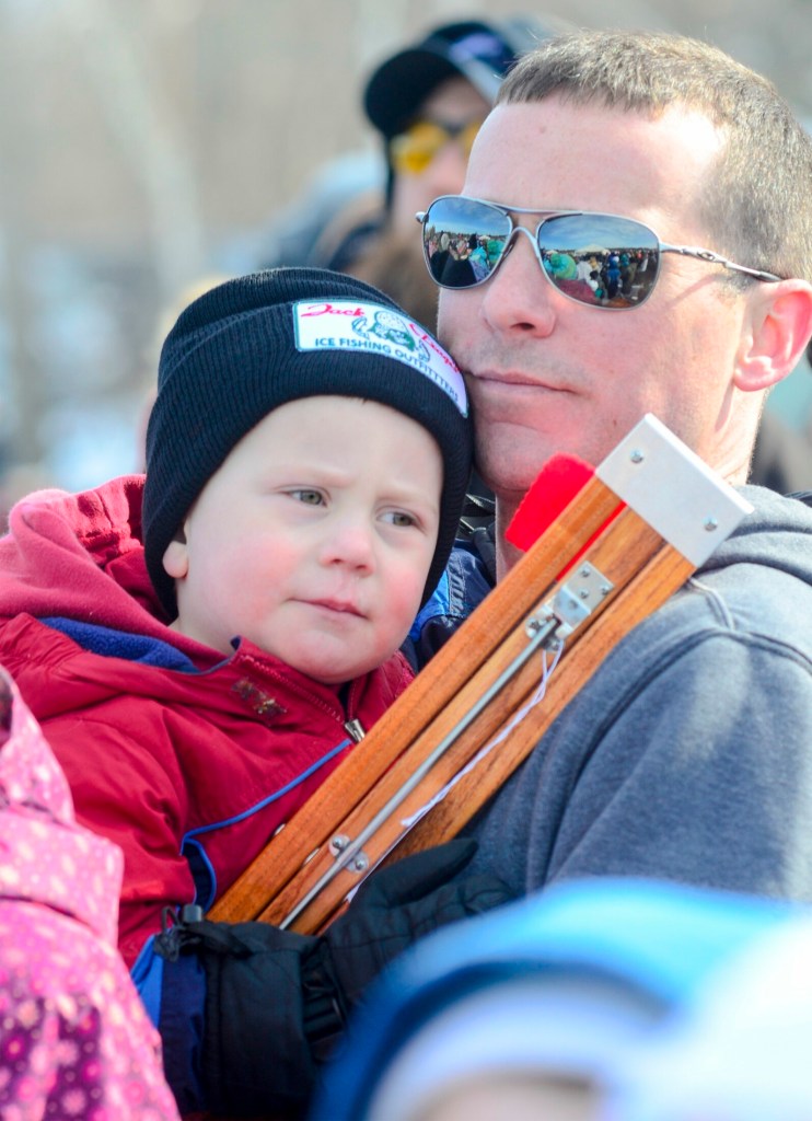 Brian Bailey holds his 3-year-old son, Sawyer Bailey, and the ice fishing trap that Sawyer won in a raffle at the children's ice fishing derby Saturday on Cochnewagon Lake in Monmouth.