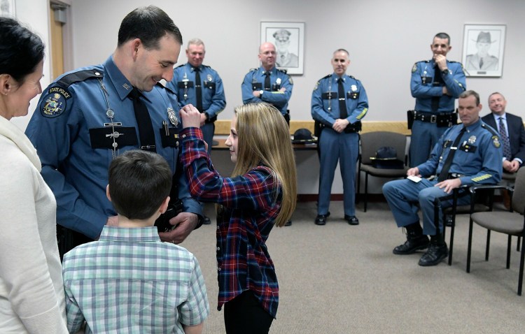 Braelyn Hood, 12, pins a Maine State Police lieutenant's badge on the chest of her father, Patrick Hood, during a promotion ceremony Monday at the Department of Public Safety in Augusta. Hood was elevated to oversee Troop D — an area that includes Knox, Sagadahoc, Lincoln, Waldo and portions of Kennebec County. Hood has served his entire 21-year career in Troop D, both as a patrol officer and sergeant, and will oversee 22 troopers. Hood replaces Lt. Aaron Hayden, who is assuming the command of the Truck Weights section of the State Police. Hood was joined by his wife, Mandy, left; son, Wyatt, 9; and the entire command staff of Public Safety, at rear.