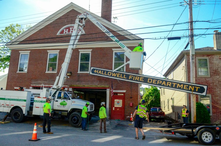 Hallowell firefighters and Pinnacle Tree Service Workers remove the sign from the old Hallowell Fire Department on Second Street on June 12, 2018, in Hallowell.
