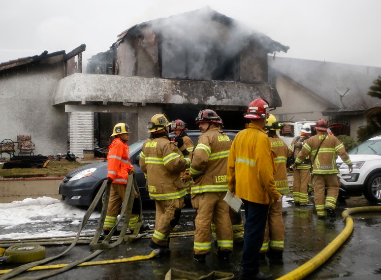 Firefighters suppress a fire at the scene of a deadly plane crash in the residential neighborhood of Yorba Linda, Calif., Sunday, Feb. 3, 2019. The Federal Aviation Administration said a twin-engine Cessna 414A crashed in Yorba Linda shortly after taking off from the Fullerton Municipal Airport. 