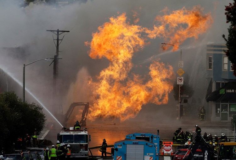 San Francisco firefighters battle a fire Wednesday that shot flames high into the air and burned several buildings as utility crews scrambled to shut off the flow of gas.