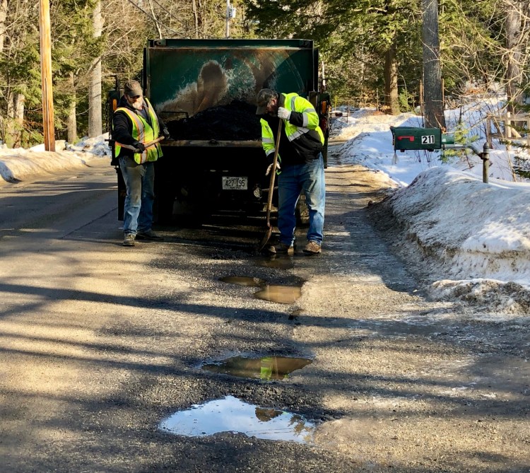 Winthrop Public Works employees David Boucher, left, and Gary Vigue patch holes Tuesday on Memorial Drive in Winthrop. 