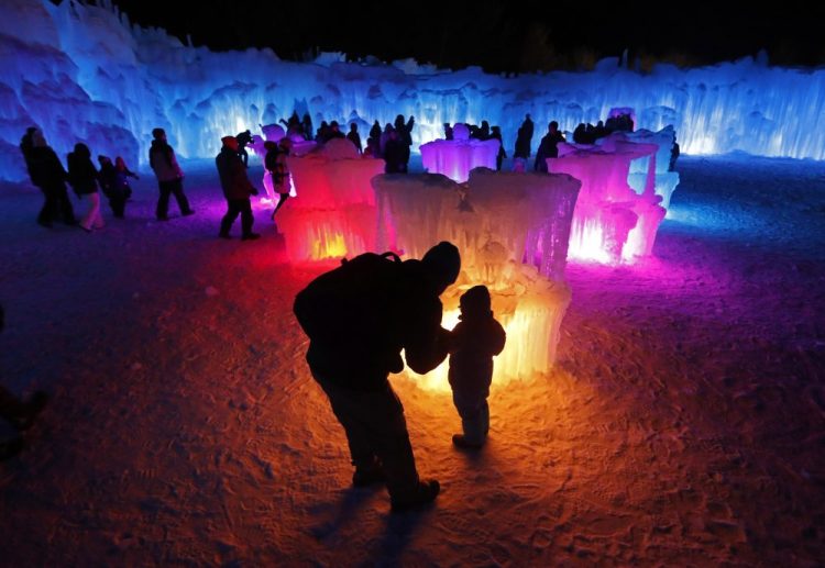 In this Saturday, Jan. 26, 2019 photo, Bruce McCafferty and his son, Dougie, pause while exploring the ice formations growing at Ice Castles in North Woodstock, N.H. 