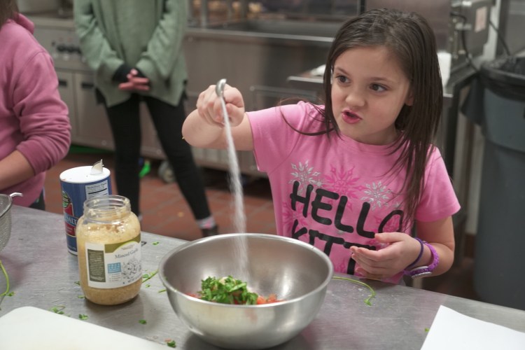 Lexi Lepage, at student at the Albert S. Hall School in Waterville, adds salt to her pico de gallo during the Sprout Scouts' field trip to the Mid Maine Technical Center in Waterville. Lexi is a member of her school's Sprout Scouts where they learn about cooking and gardening.