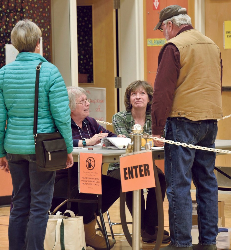 Norridgewock election clerks Kay Laney, seated at left, and Kelly-Ann Withee, speak with voters Gail and Jack Gibson before they vote at the Mill Stream School prior to the annual Town Meeting on Monday.