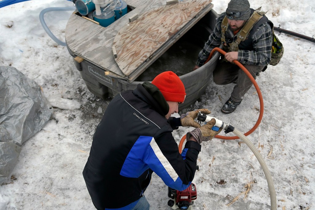 Nathan Bacon, left, and Tyler Jepson pump sap Sunday at the Bacon Farm Maple Products sugar bush in Sidney.