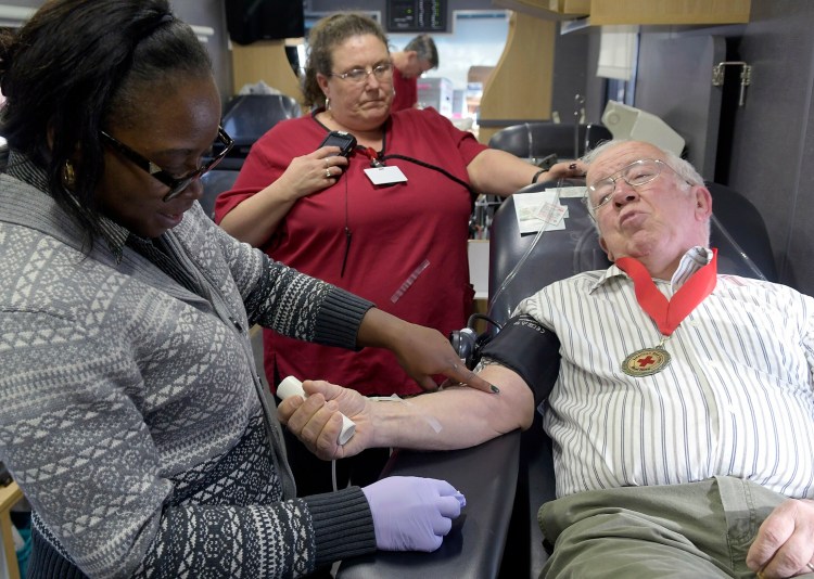 Red Cross phlebotomists Meika Reed, left,  and Laura Landry draw blood on Wednesday from Jack Schrader in a Red Cross van at the Augusta branch of Kennebec Savings Bank.