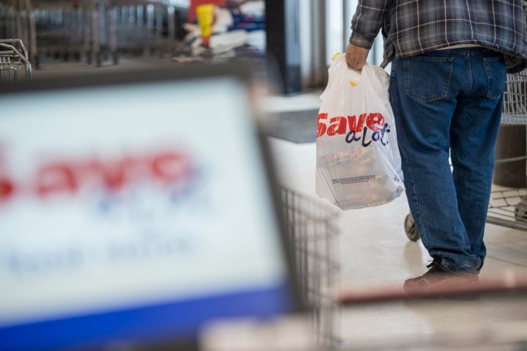 A shopper leaves with a plastic bag, purchased for an additional 10 cents, from Save-a-Lot in Waterville on Friday.